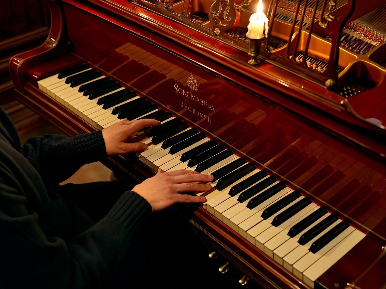 Pianist's hands at the keyboard in candlelight